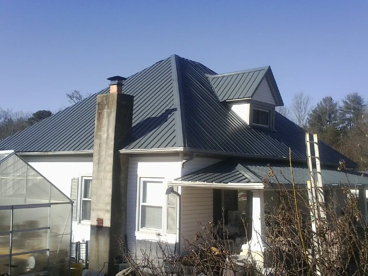 Dark blue standing seam metal roof on a white farmhouse with dormer — Slate & Tile Roof Repair by Roofing Brothers in Skaneateles