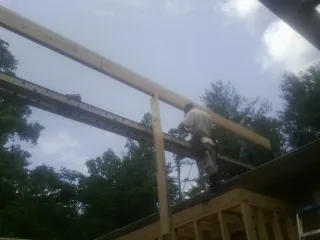 Carpenter setting a ridge beam over a new addition frame — Ice Dam Removal by Roofing Brothers in Skaneateles