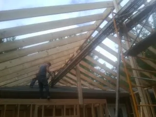 Rafters going up over a new addition with a worker on the wall in Skaneateles