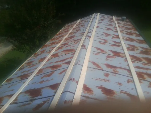 Rusted metal roof panels with new wood purlins before replacement — Storm Damage Roof Repair in Skaneateles by Roofing Brothers