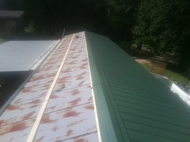 Old rusted panels beside newly installed green metal roofing — Wind Damage Roof Repair by Roofing Brothers in Skaneateles
