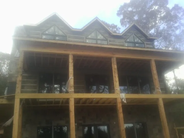 Dormers and porch framing on a large log home under construction — Roof Coating work by our crew in Skaneateles