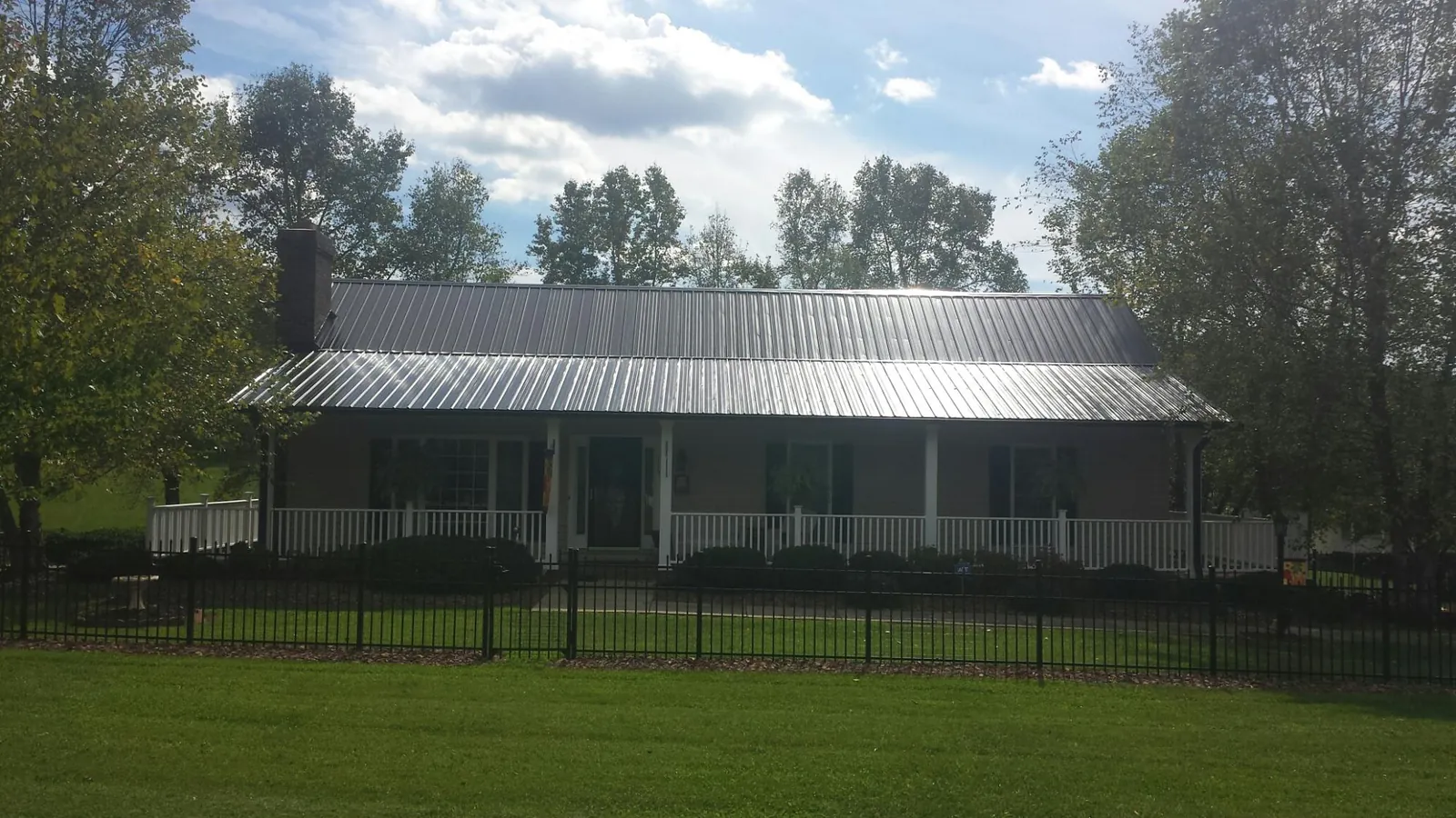 Gray metal roof on a brick ranch with a full width front porch — Gutter Guard Installation work by our crew in Skaneateles