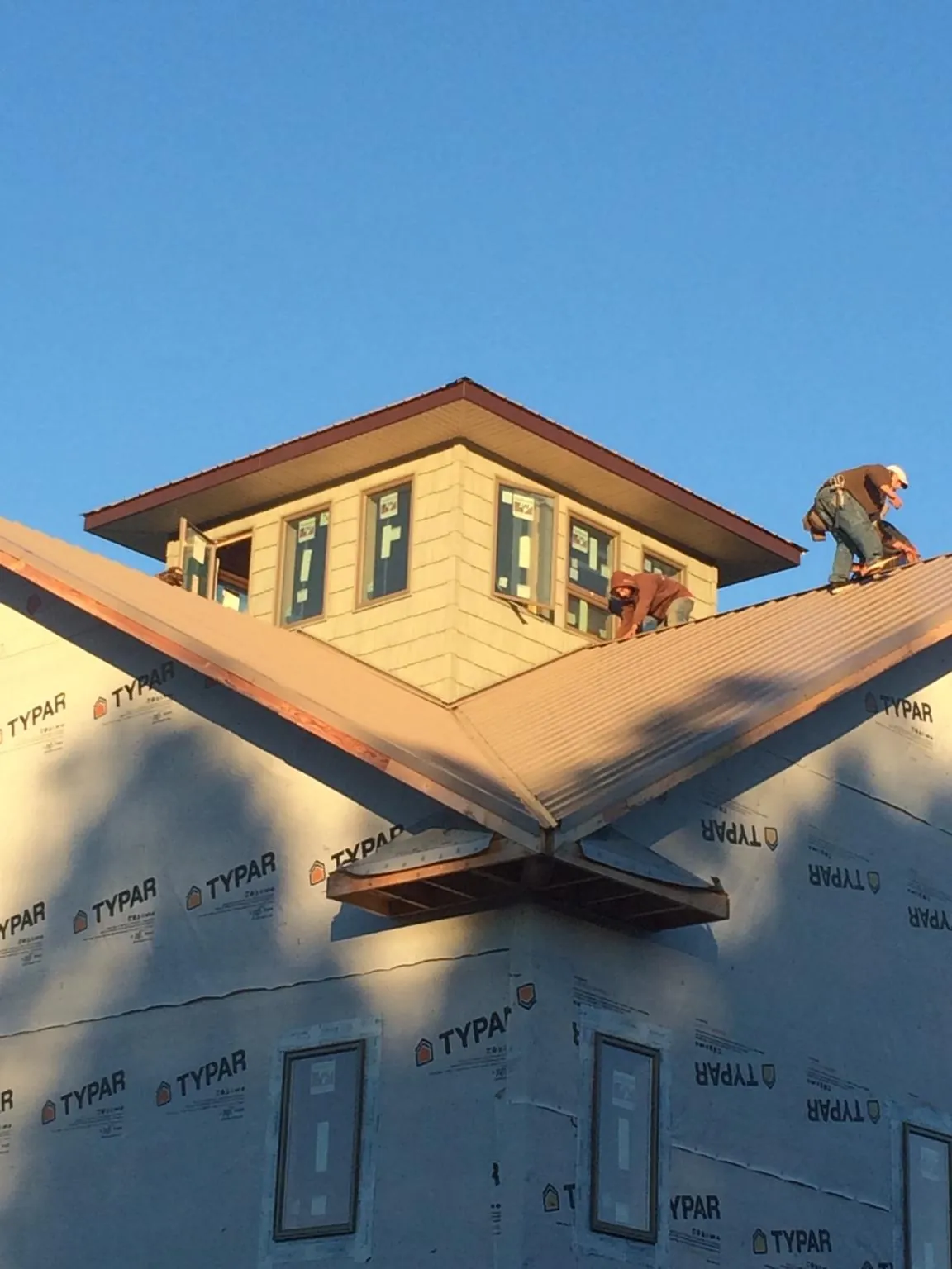 Roofers working around a rooftop cupola on a new metal roof at sunset — Roof Waterproofing in Skaneateles by Roofing Brothers